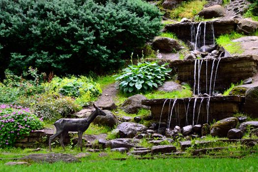 Waterfalls in public garden and statue of roe. Tallinn, Estonia.