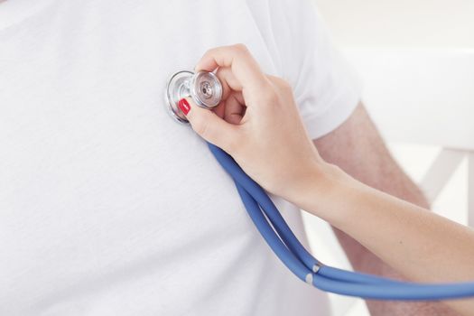 Doctor examining heartbeat with stethoscope, close-up view