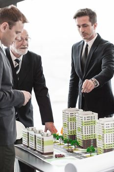 Business meeting of architects and investors looking at model of residential quarter houses