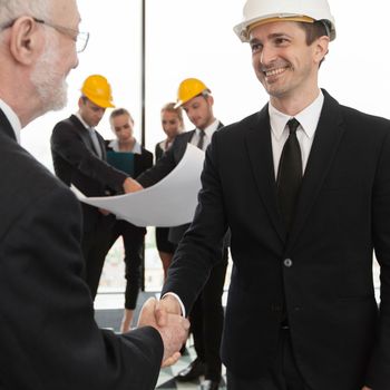 Handshake of architect and investor, business team with blueprint on background