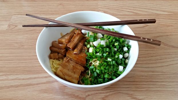 Egg noodle with steam pork belly in a bowl with chopsticks