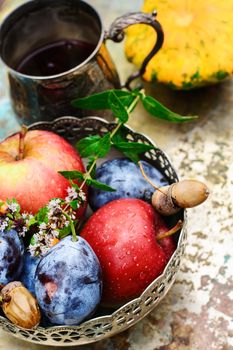 Stylish metal bowl with apples,plums and acorns in the autumn still life