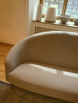 Elegant sofa in a room with big window, decorated with ceramic artwork.