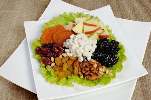 Vitamin salad with nuts, apples, dried fruit and cottage cheese in lettuce leaves