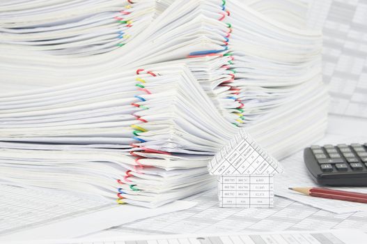 House and pile paperwork of report with colorful paperclip on finance account have blur pencil and calculator as background.