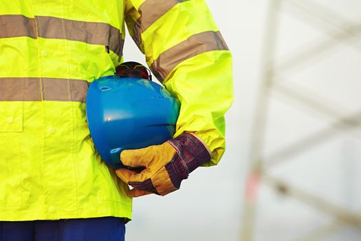 Arm of worker is holding protective helmet