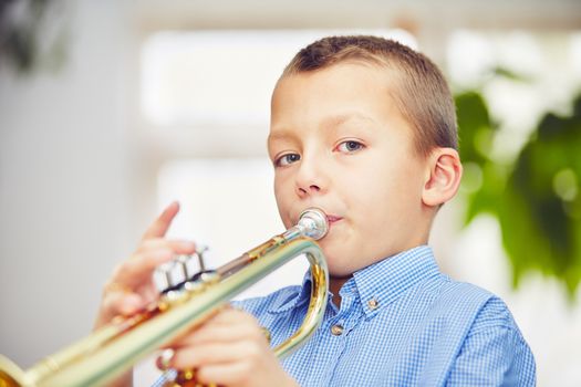 Little boy is playing the trumpet at home 