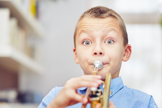 Little boy is playing the trumpet at home 