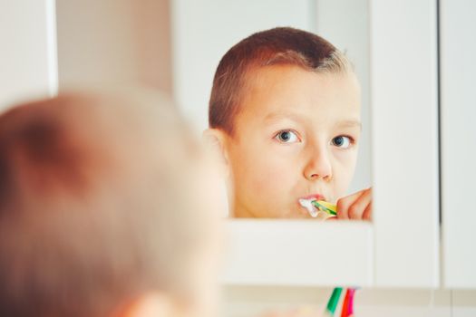 Everyday life at home. Little boy is cleaning teeth in the bathroom. - selective focus