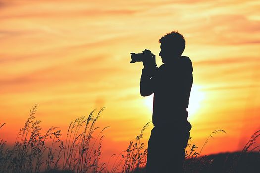 Silhouette of the young photographer at the sunset.