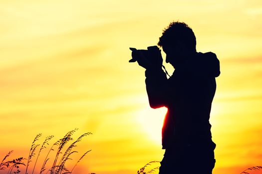 Silhouette of the young photographer at the sunset.