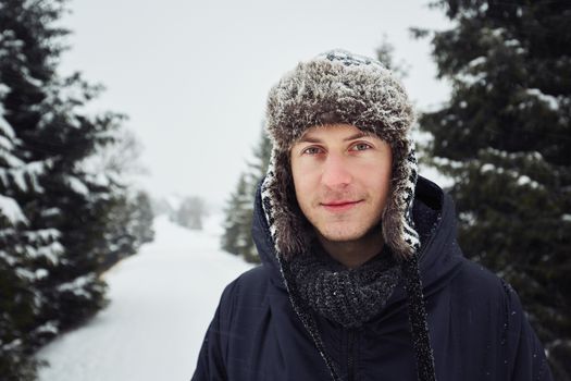 Portrait of young man outdoors in winter under snowstorm