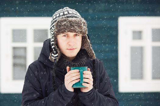 Portrait of young man outdoors in winter under snowstorm