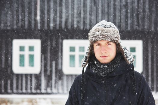 Portrait of young man outdoors in winter under snowstorm