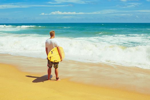 Man with surfboard on the beach at sunset.  