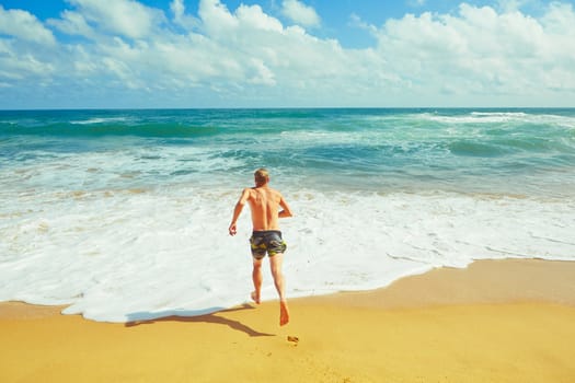 Young man is running to the sea