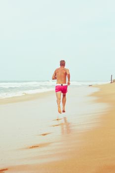 Young man is running on the beach