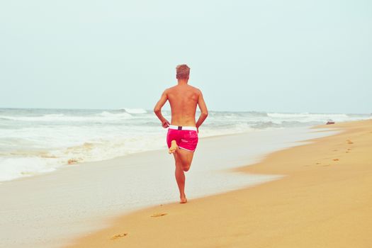 Young man is running on the beach