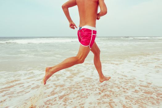 Young man is running on the beach