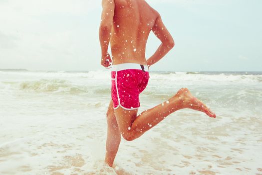 Young man is running on the beach