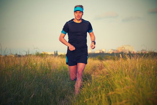 Young man is running on summer meadow - lovely sunset light