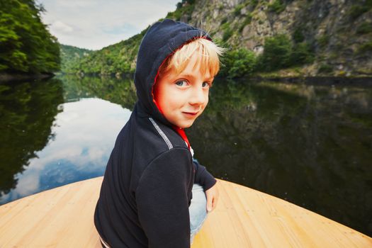 Little traveler on the river. Boy is sitting on the boat.