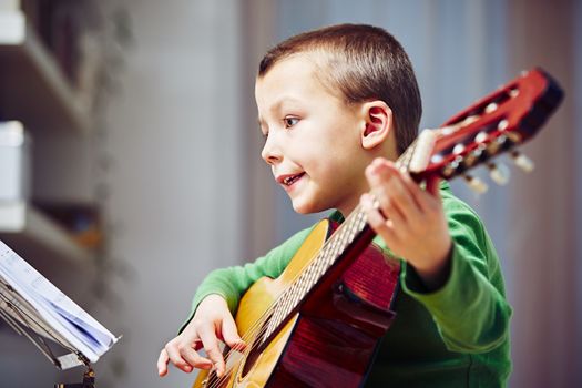 Little boy is playing the guitar at home