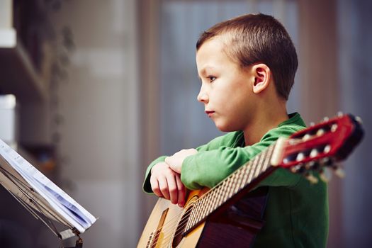 Little boy is playing the guitar at home