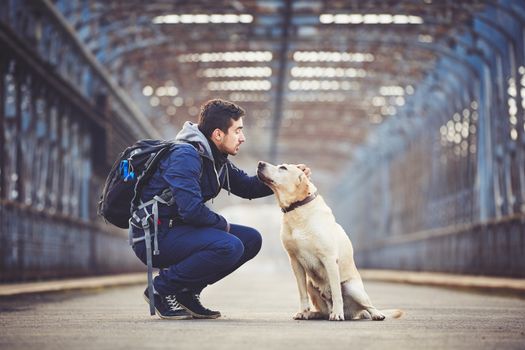 Man with his yellow labrador retriever on the old bridge