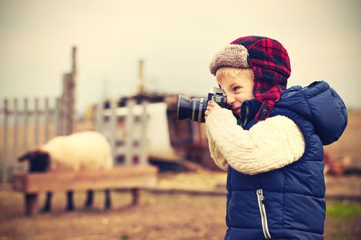 Little boy with camera is shooting in the farm