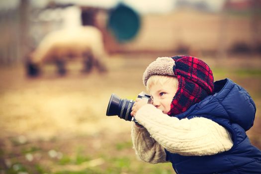 Little boy with camera is shooting in the farm