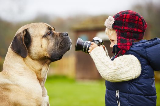 Little boy with camera is shooting his dog