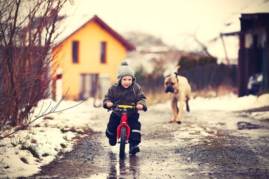 Little boy is playing with his dog on the street.