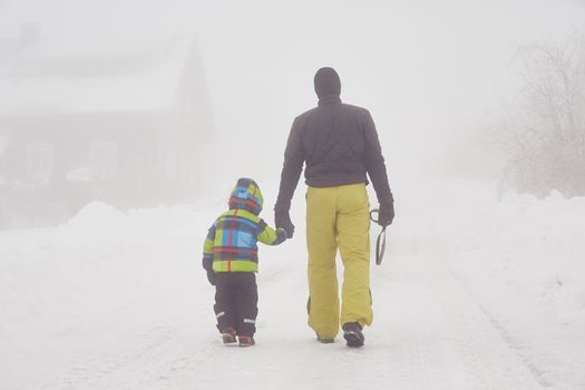 Father with son are walking in mountains in winter