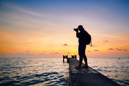 Young photographer is taking photos at the sunset.