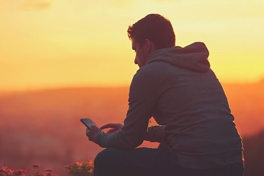 Young man with phone at the sunrise.