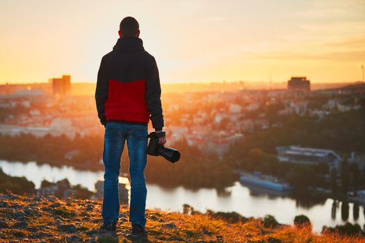 Young photographer is enjoying sun. Photographer with mirror camera is ready to take sunrise pictures.