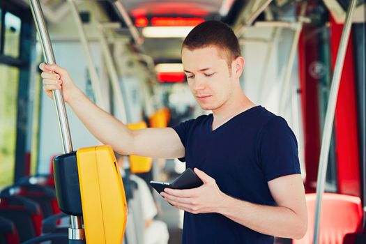 Everyday life and commuting to work by bus (tram). Handsome man is paying transport ticket with mobile phone. 