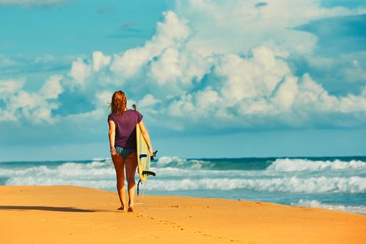Beautiful surfer girl is enjoying vacation on the tropical beach. Young woman with surfboard in Sri Lanka. 