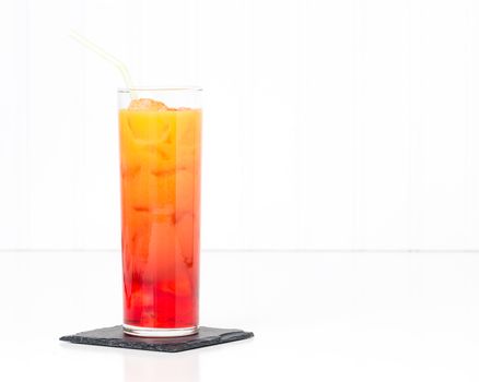 Tropical cocktail known as a tequila sunrise in a tall glass.