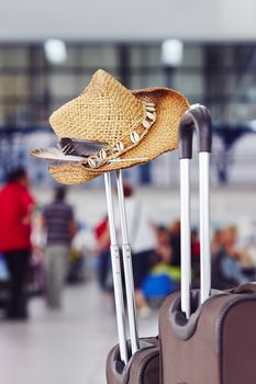 Luggage with straw hat at the airport terminal