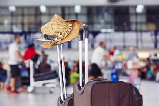 Luggage with straw hat at the airport terminal