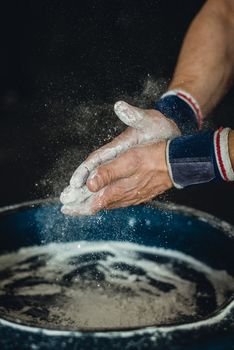 Chalking hands to prepare for weightlifting.