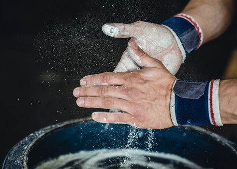 Chalking hands to prepare for weightlifting.