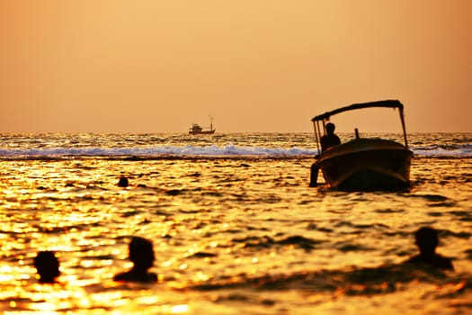 Fishing boat and silhouettes people in the sea - selective focus