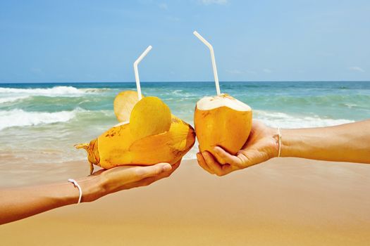 Hands of the couple with coconut drinks