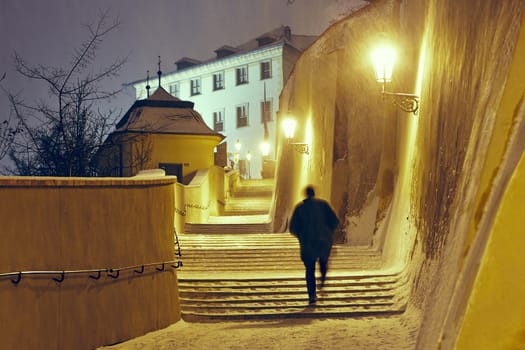 Snowfall in the city - man is walking in narrow street in Prague