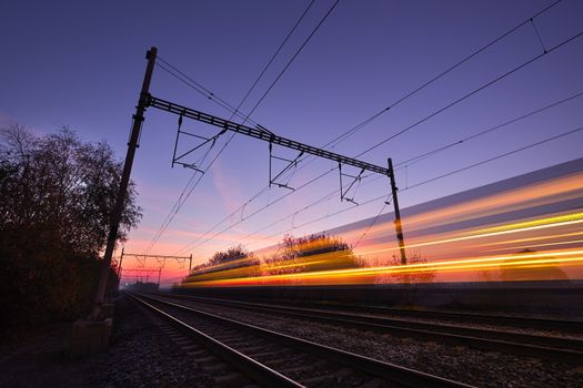 Passenger train on railroad tracks at the sunrise - blurred motion