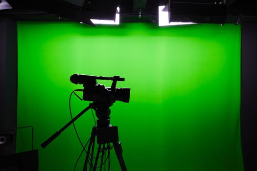 Silhouette of digital video camera in front of the green screen