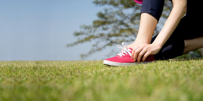 Running shoes - closeup of woman tying shoe laces on her barefoot running shoes. Female sport fitness runner getting ready for jogging outdoors.